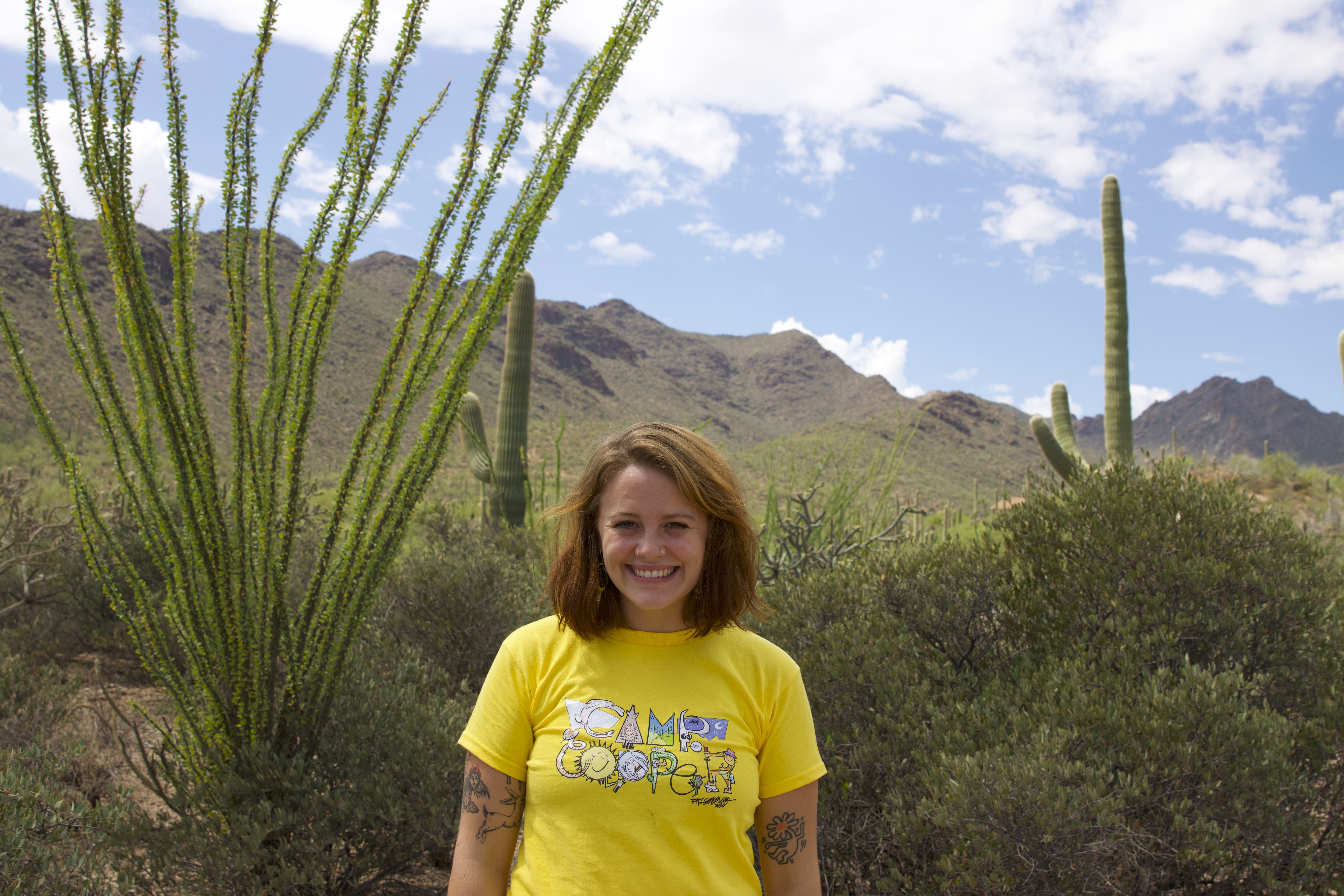 Aliya McDonald wearing a yellow shirt outside under a sunny sky with desert scenery in the background