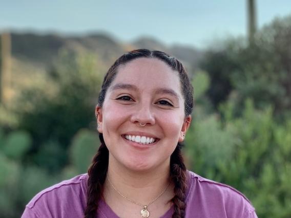 A picture of staff member Alexianne in a purple shirt, with two braids, in a desert setting. 
