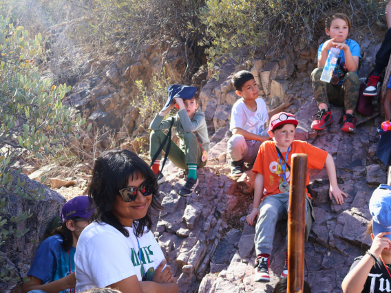 group of kids sitting on rocks taking a break in desert landscape