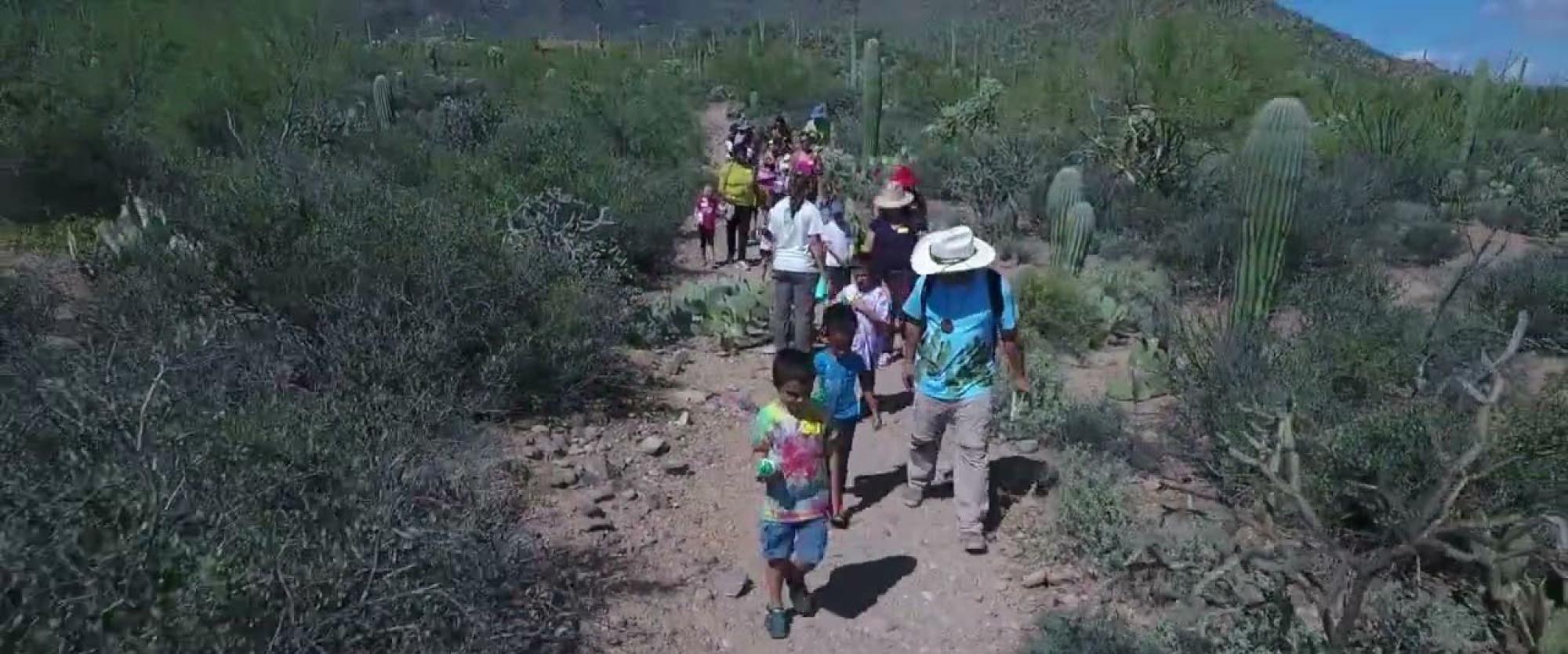 aerial footage of the desert with kids and adults walking a trail